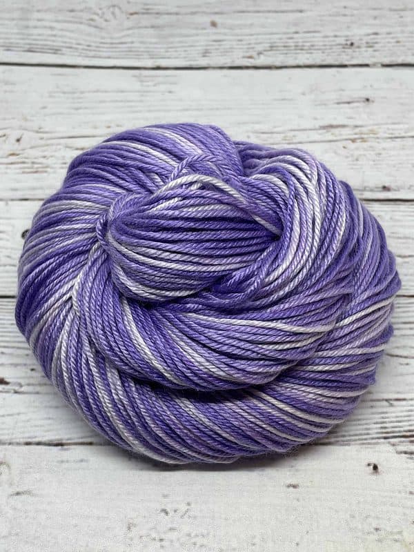 Tonal light purple and white yarn wrapped into a snail-shaped ball.